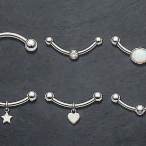 Illustrative stainless steel navel rings arranged in a set on a plain background